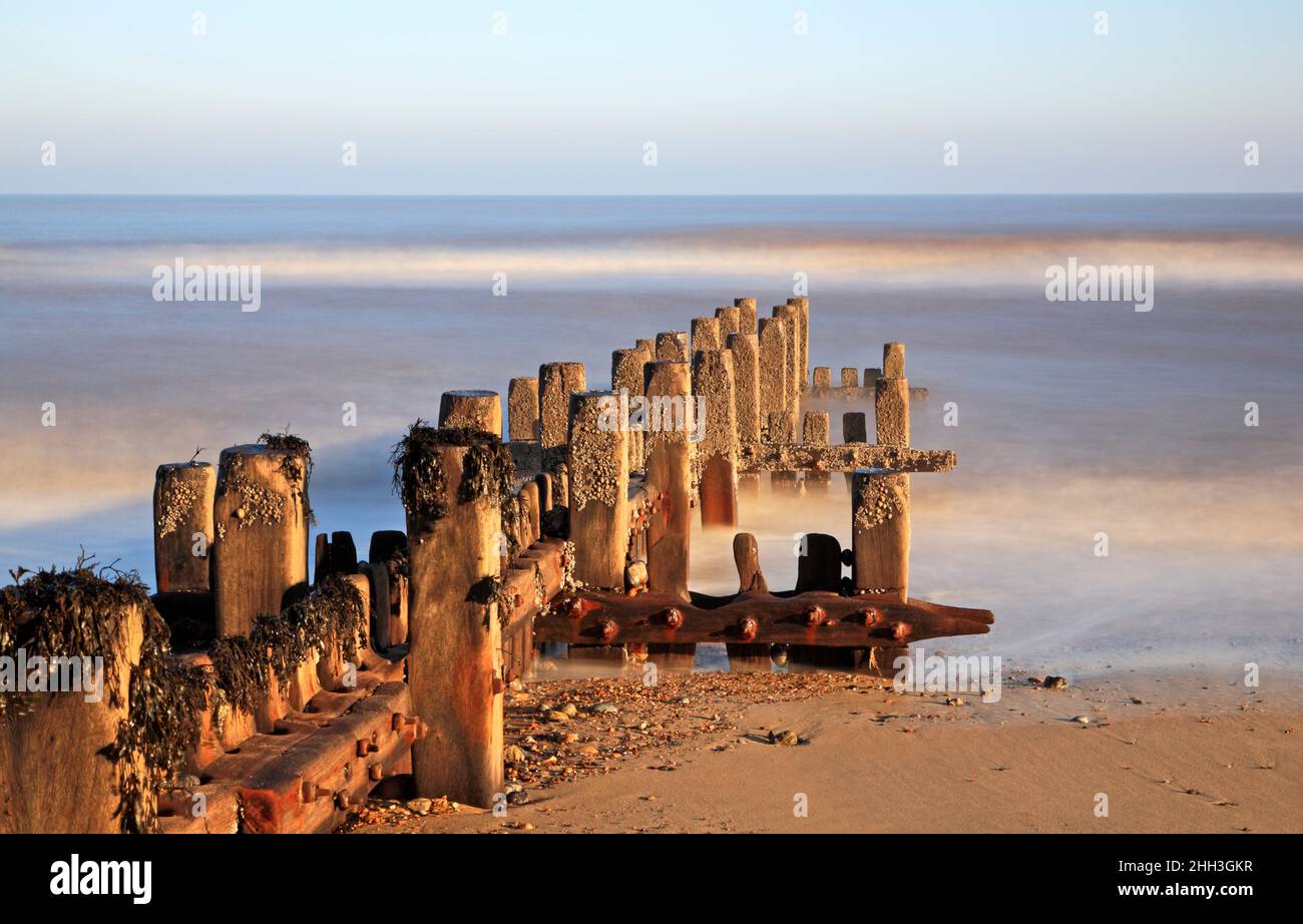 A fine art study of a deteriorating wooden breakwater utilizing a long exposure in North Norfolk at Cart Gap, Happisburgh, Norfolk, England, UK. Stock Photo