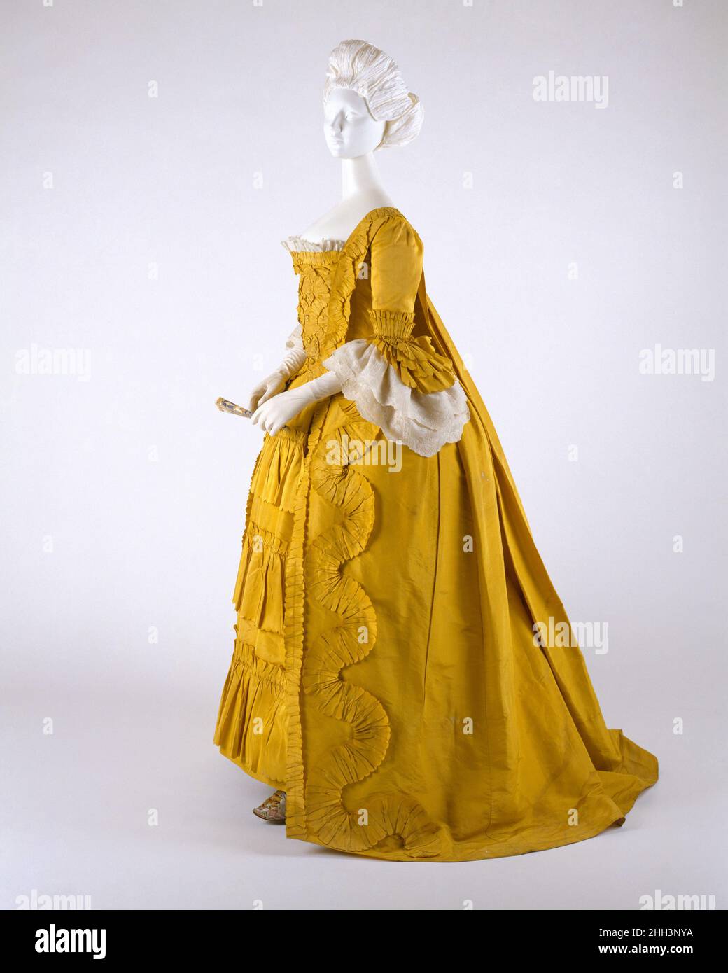 Dress ca. 1760 British Monochrome, but in a bright canary yellow guaranteed to catch anyone's attention across a room, this exceptionally well-preserved robe à la française with trimmings represents the apogee of the form. The absence of ornament, other than basic ruffles, makes this a museum object easy to read: it is a perfect teaching example, free from distractions and affirming thereby the adorned beauty of eighteenth-century silhouette and style, so often masked under frills and coquetry.. Dress. British. ca. 1760. silk, linen, cotton Stock Photo