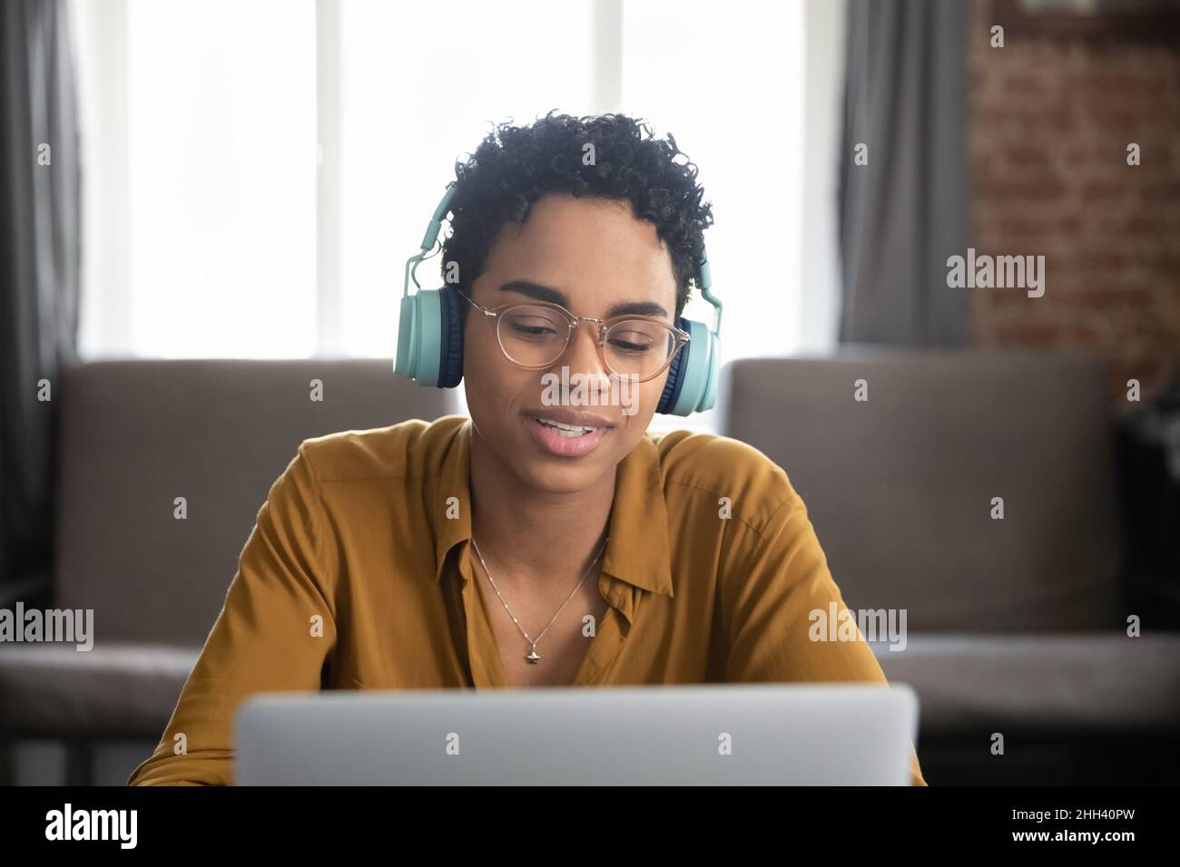 Happy Black student girl wearing big cool headphones watching webinar ...