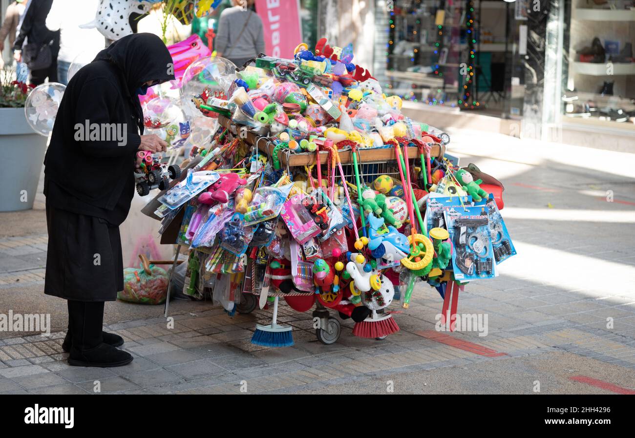 Elder woman selling children toys in the streets. Grandmother wearing black cloths working. Nicosia Cyprus Stock Photo