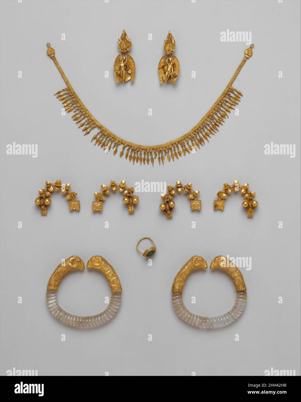 Ganymede jewelry ca. 330–300 B.C. Greek The pieces in this group are said to have been found together in Macedonia, near Thessaloniki, before 1913. The assemblage forms an impressive parure (matched set) - earrings, necklace, fibulae (pins), bracelets, and a ring - but it is not certain that they belong together, for the pieces do not show a clear uniformity of style.The gold strap necklace, dated circa 300 B.C., is made of three double loop-in-loop chains with double interlinking and a fringe of beechnut pendants. The terminals take the form of an ivy or grape leaf and have a border of beaded Stock Photo