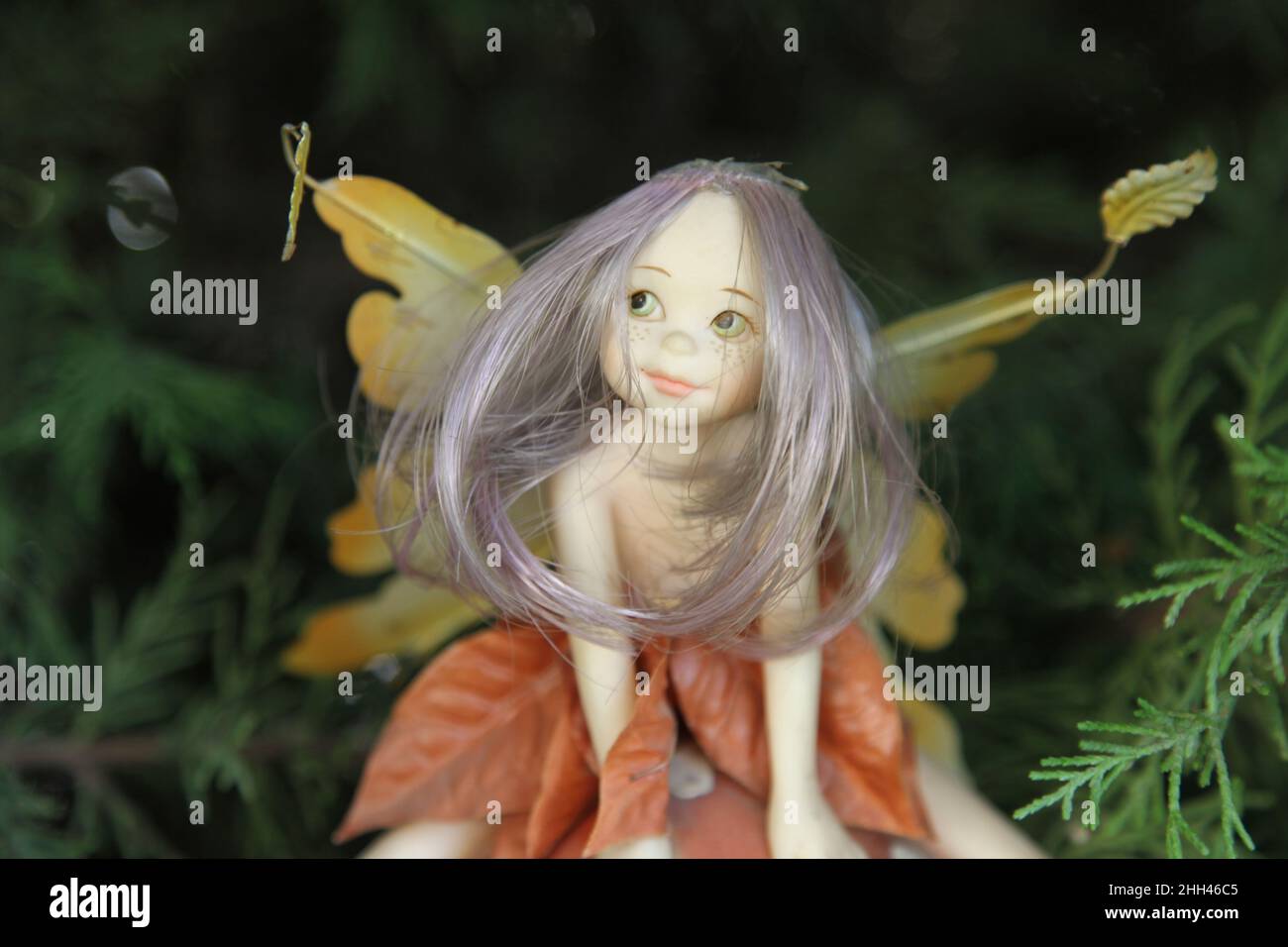 A long-haired fairy with wings figurine sitting in the garden. Close up Stock Photo