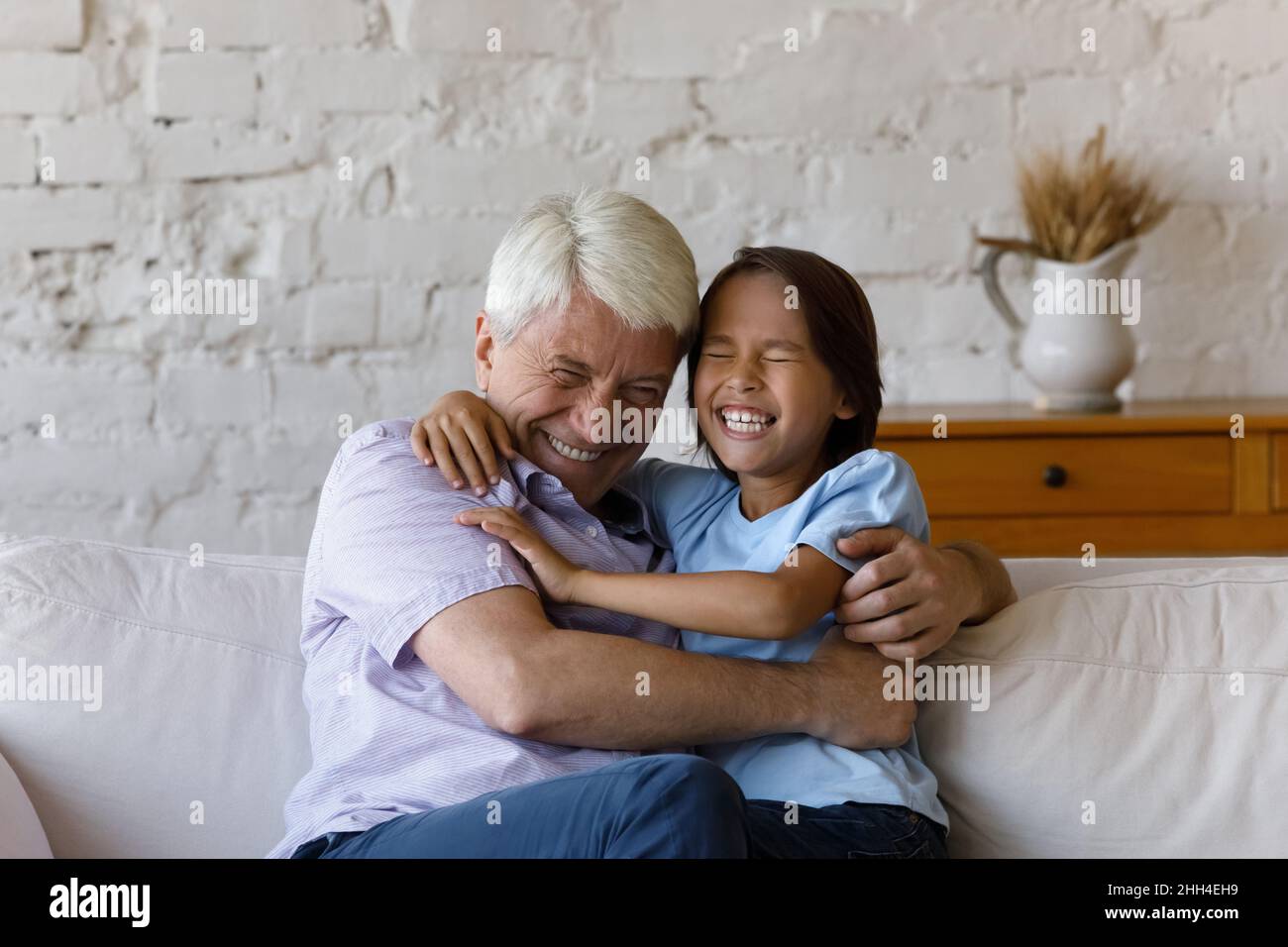 Happy cheerful granddad cuddling, tickling excited laughing grandkid boy Stock Photo