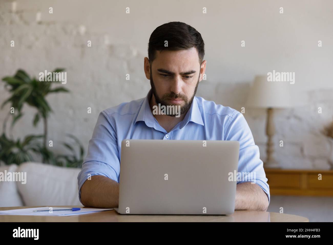 Focused millennial business man using laptop at table Stock Photo
