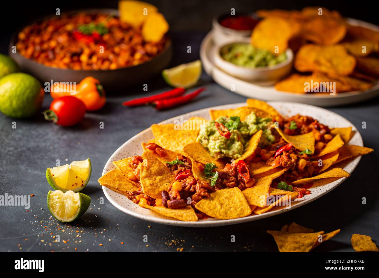 Delicious plate of yellow corn nachos chips with cheese, minced meat and red hot spicy salsa