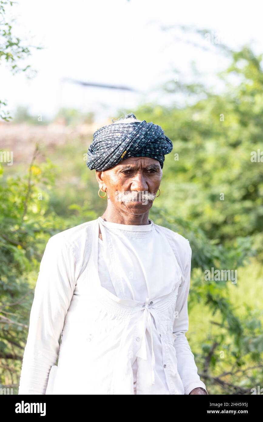 Jawai, Rajasthan, India - September 2021: Portrait of a male shepherd of the Rabari ethnic group in a national headdress and traditional white dress, Stock Photo