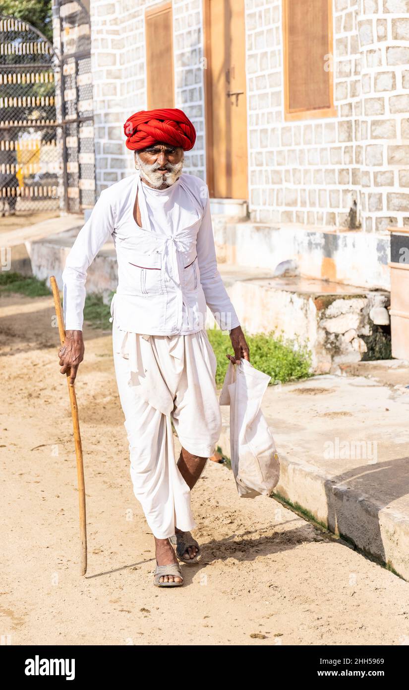 Jawai, Rajasthan, India - September 2021: Portrait of a male shepherd of the Rabari ethnic group in a national headdress and traditional white dress, Stock Photo