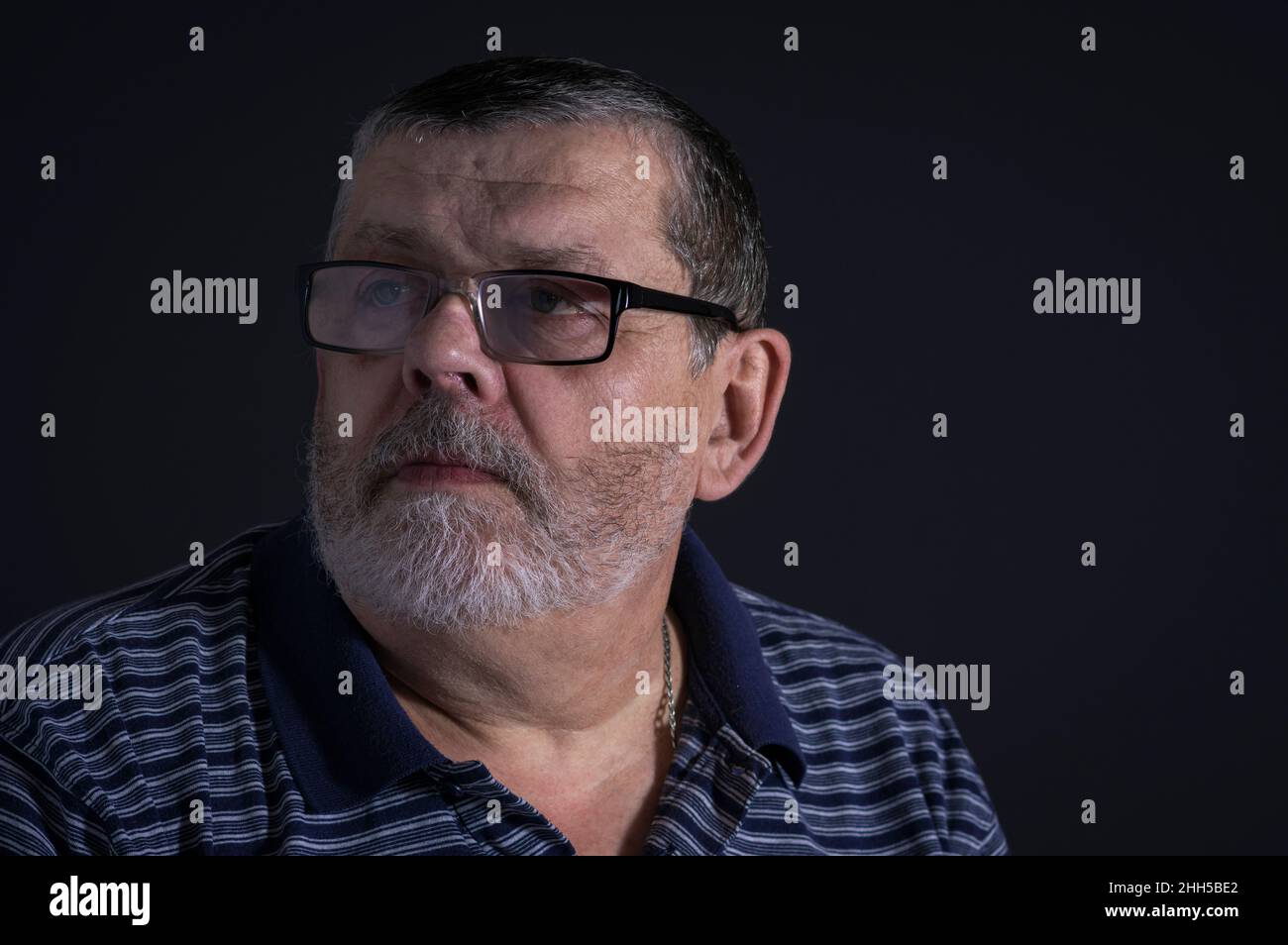 Nice portrait of meditating Caucasian senior man in glasses against dark background Stock Photo