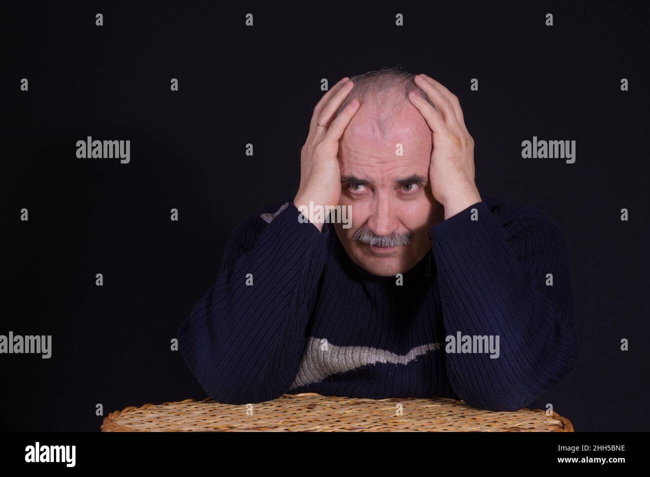 Nice portrait of thoughtful Caucasian mature man  with arms enfolded head  in low key Stock Photo