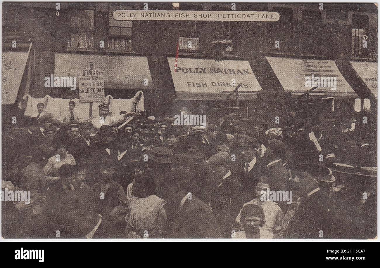 Polly Nathan's fish shop, Petticoat Lane, early 20th century: large crowd in the street (men, women and children). A sign for 'Polly Nathan, Fish Dinners' is in the background. A sign for a sale by F. Littman & Company is also on display Stock Photo