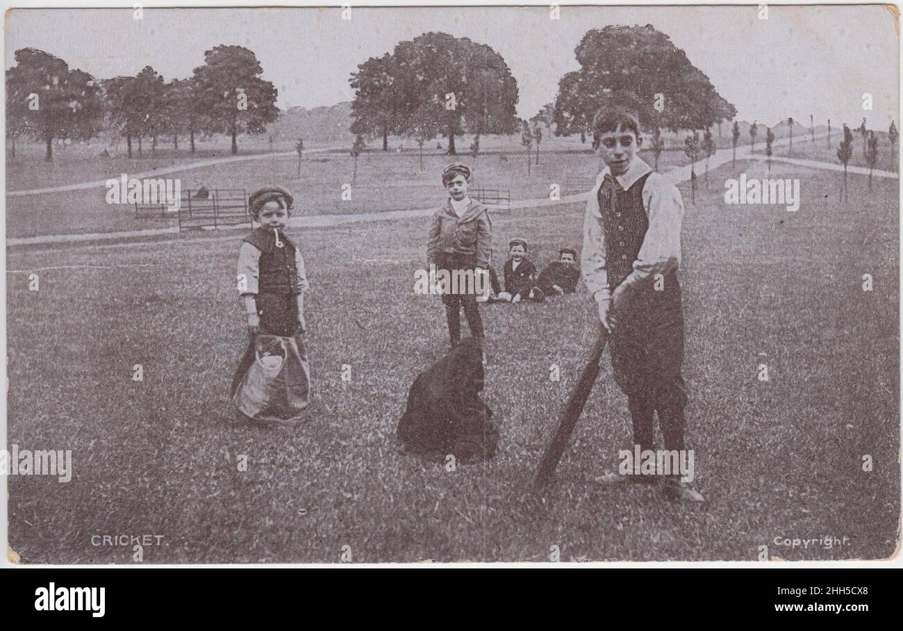 Children playing cricket in the park, bags are being used as stumps and one small child appears to be smoking a clay pipe. The postcard was sent in 1907 Stock Photo
