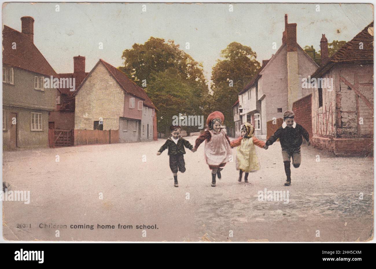'Children coming home from school': two boys and two girls running hand in hand down a village road. The postcard was sent in 1906 Stock Photo