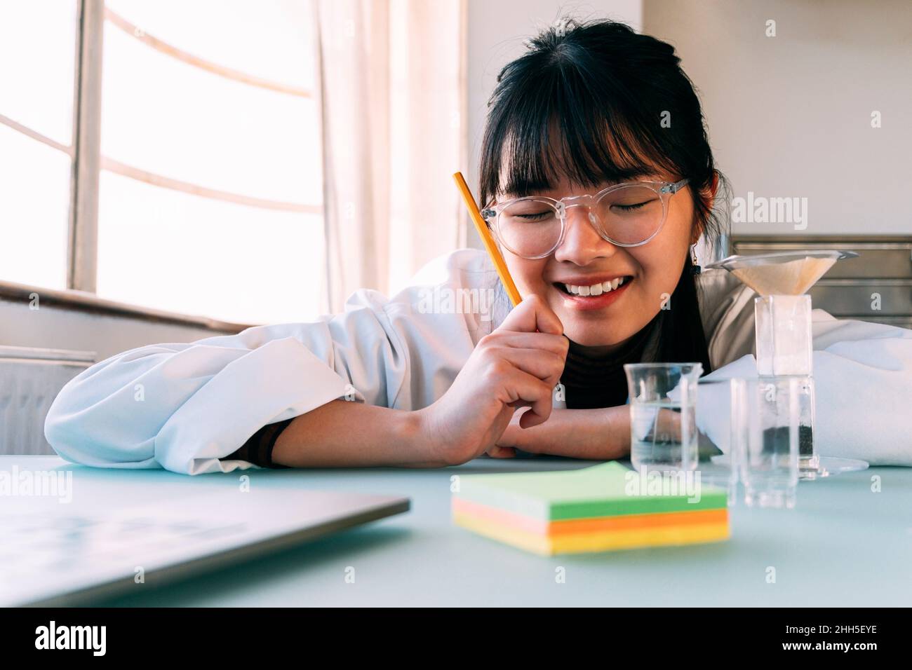 Happy scientist with pencil leaning on table in laboratory Stock Photo ...