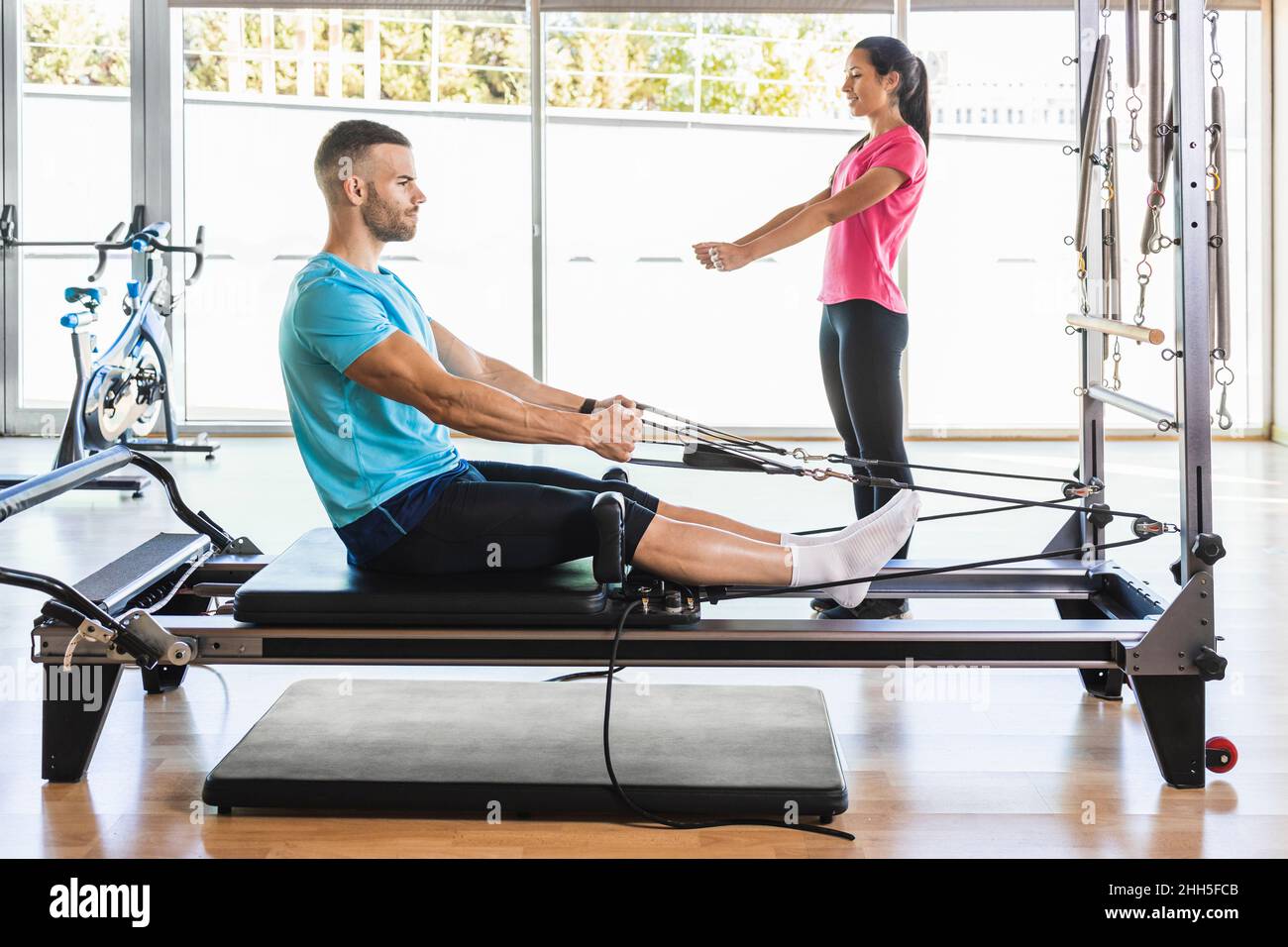 Fitness instructor showing exercise to athlete on exercise equipment Stock Photo