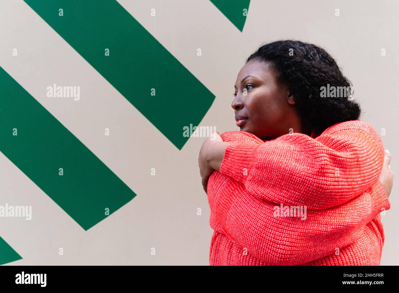 Plus size woman wearing red sweater hugging self Stock Photo