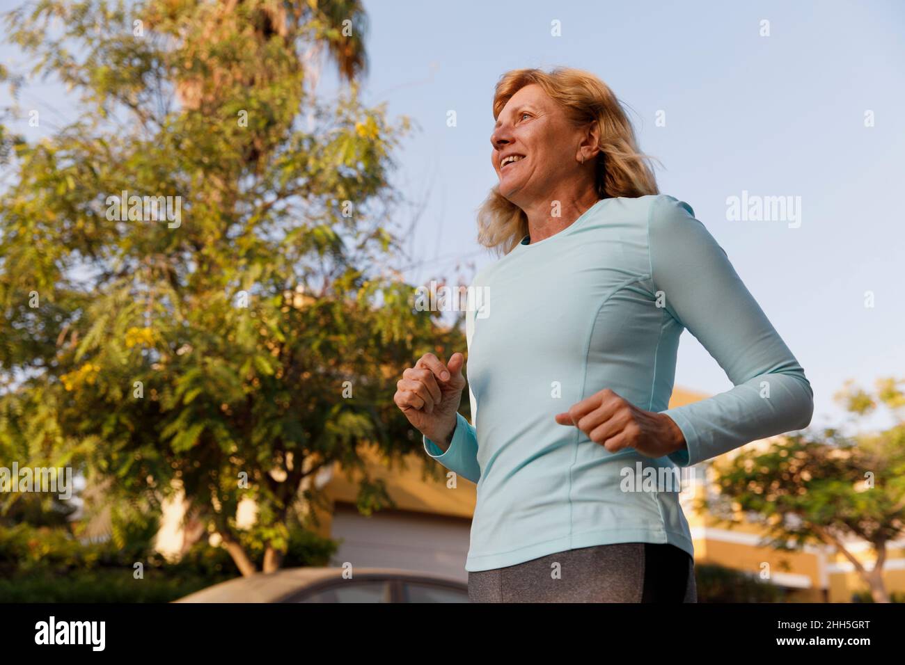 Smiling active senior woman running at park Stock Photo