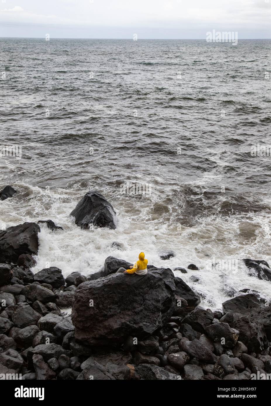 Young man on volcanic rock looking at sea, Rocha Da Relva, San Miguel Island, Azores, Portugal Stock Photo