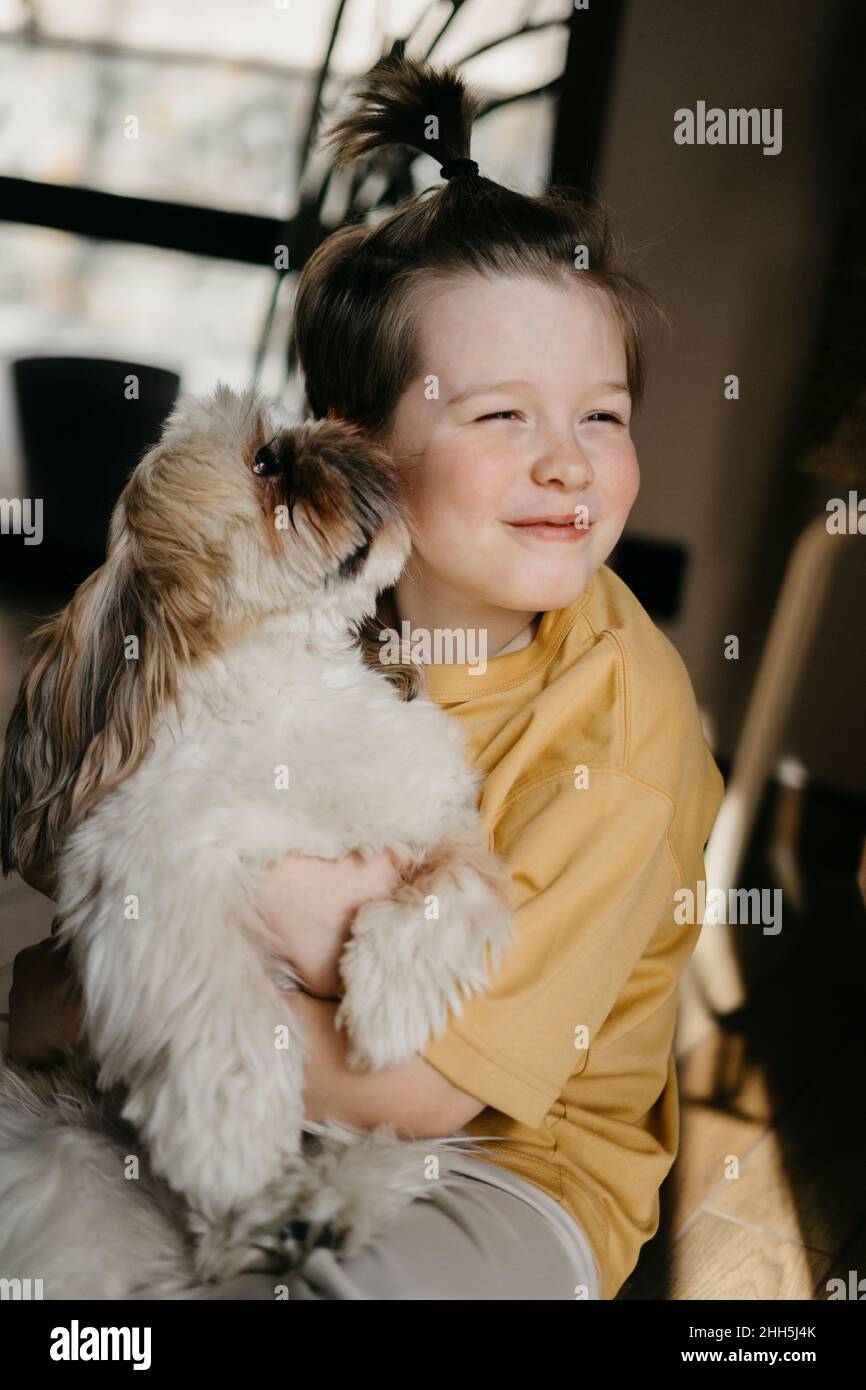Dog licking boy's cheek at home Stock Photo