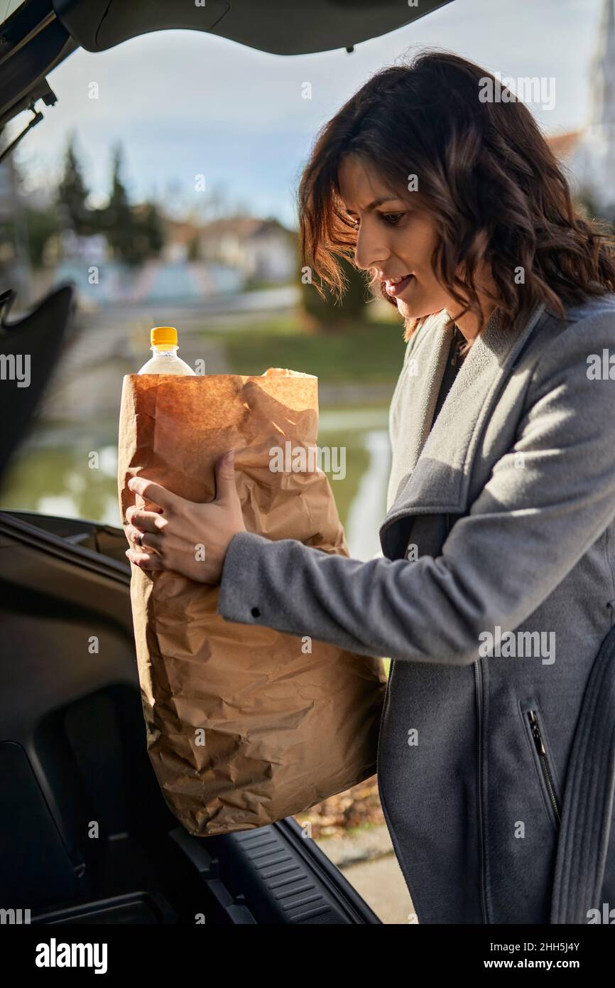 Woman putting grocery bag in car trunk Stock Photo Alamy