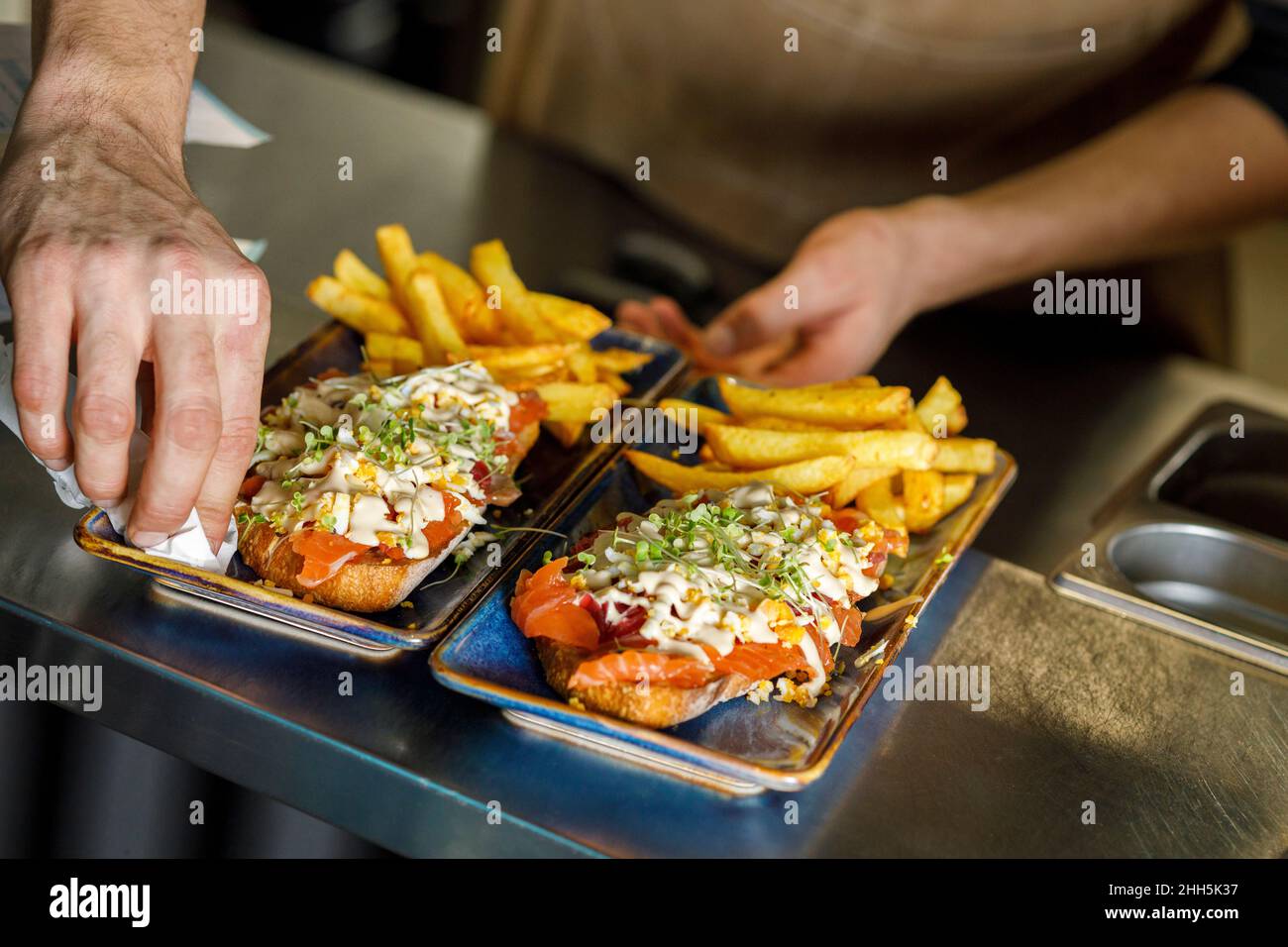 Chef cleaning serving dish at restaurant counter Stock Photo