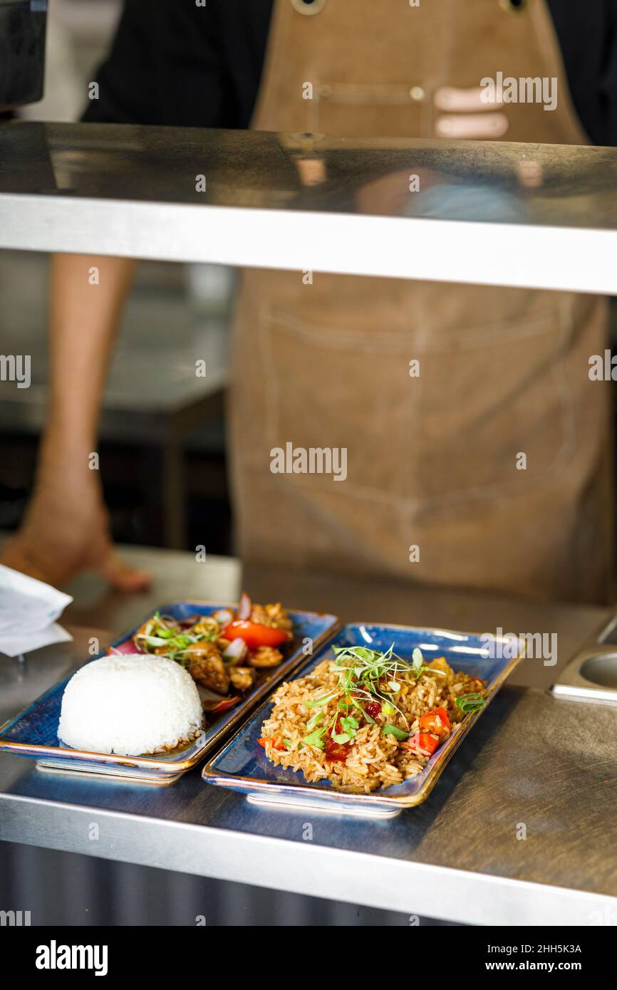 Chef with cooked food in tray at restaurant counter Stock Photo
