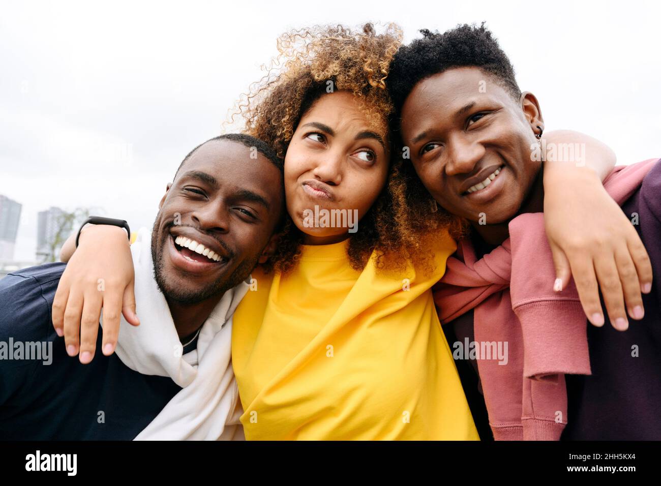 Woman making facial expression with smiling friends in front of clear sky Stock Photo