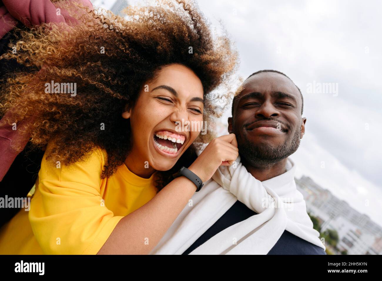 Happy young woman pulling cheek of friend outdoors Stock Photo Alamy
