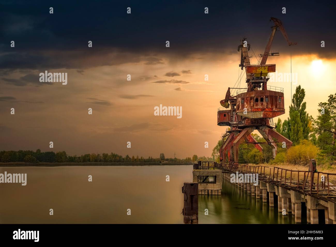 Ukraine, Kyiv Oblast, Pripyat, Abandoned crane on bank of Pripyat River at sunset Stock Photo