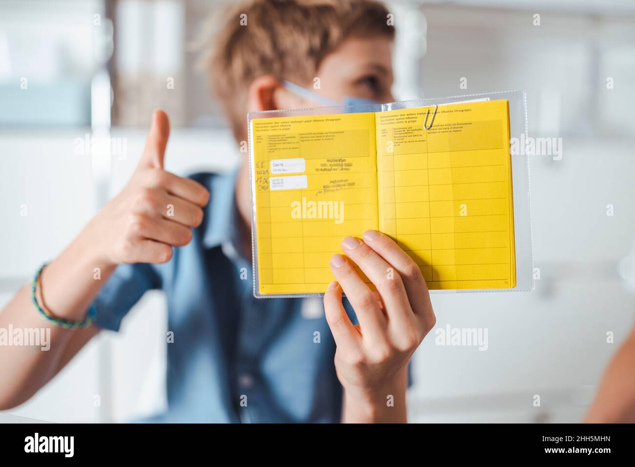 Boy showing thumbs up and holding vaccination certificate at center Stock Photo