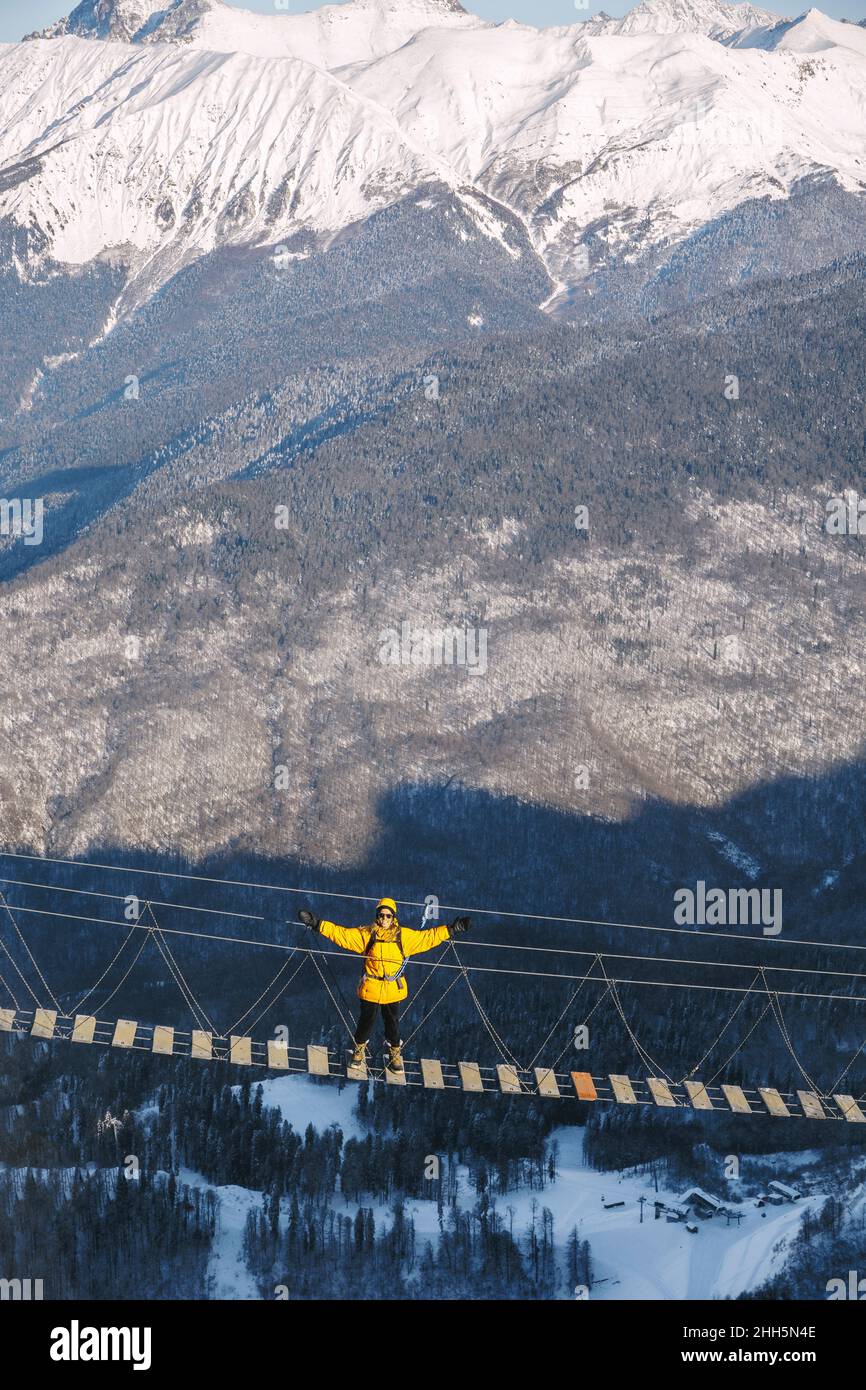 Adventurous man with arms outstretched standing on rope bridge Stock ...