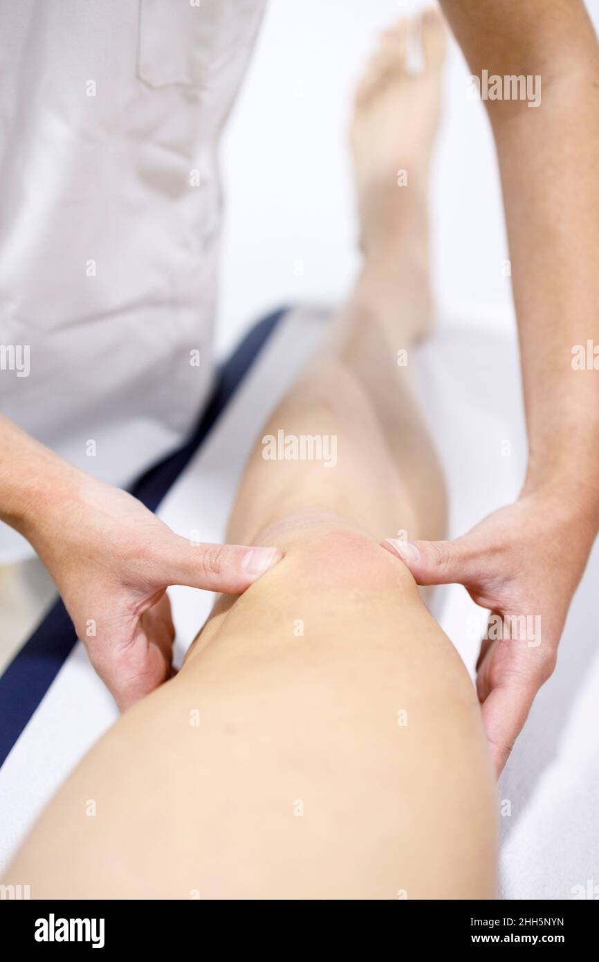 Physical therapist massaging sportsman's leg on table Stock Photo