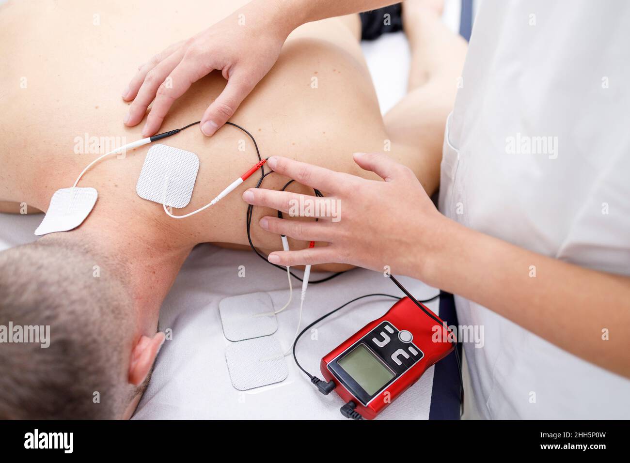 Physical therapist applying electrodes on athlete's neck Stock Photo