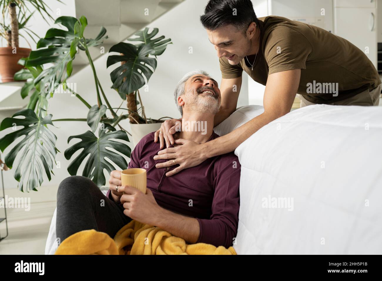 Gay men smiling at each other in living room Stock Photo