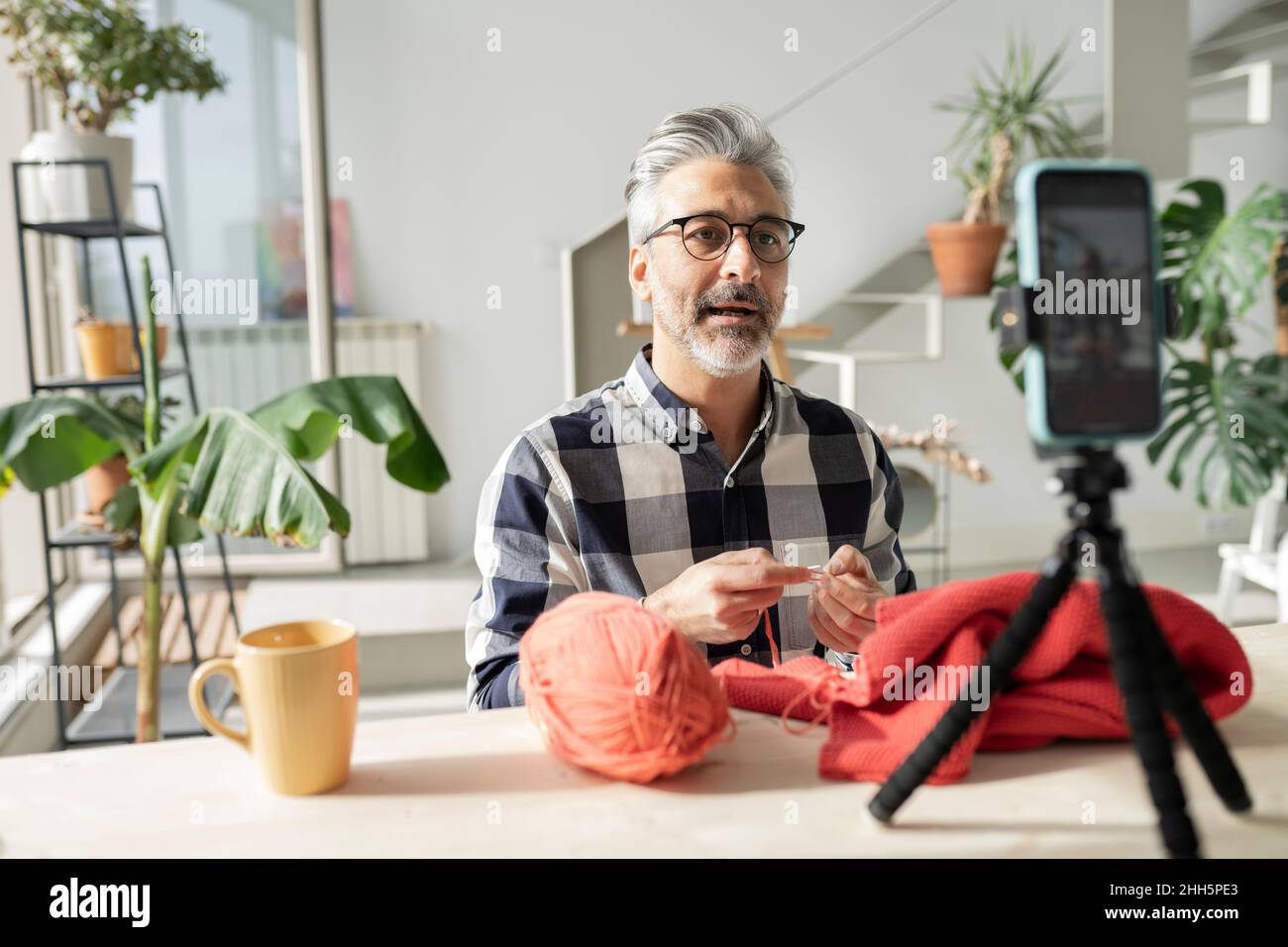 Man making video tutorial on knitting using smart phone at home Stock Photo