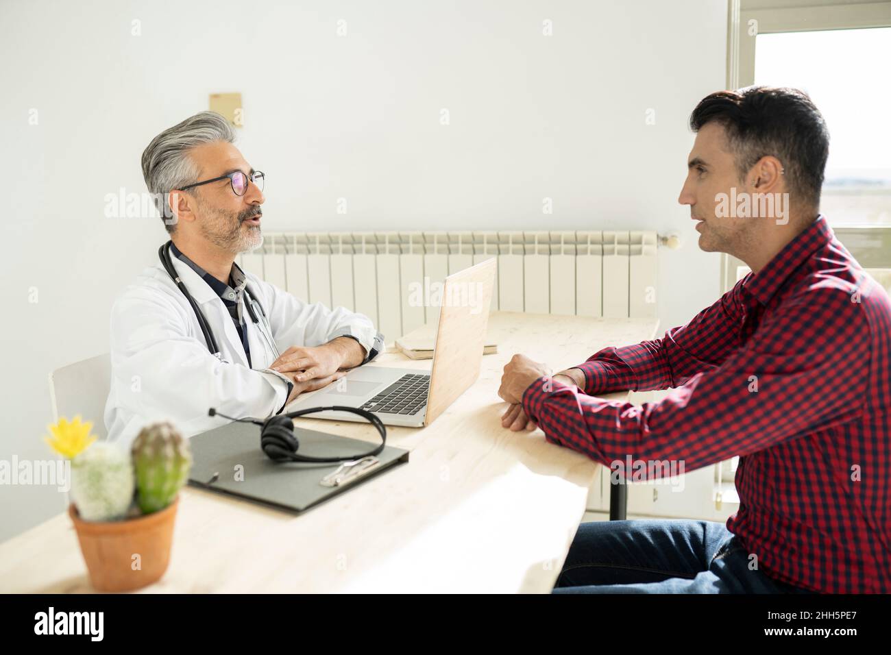 Doctor discussing with patient sitting at desk Stock Photo - Alamy