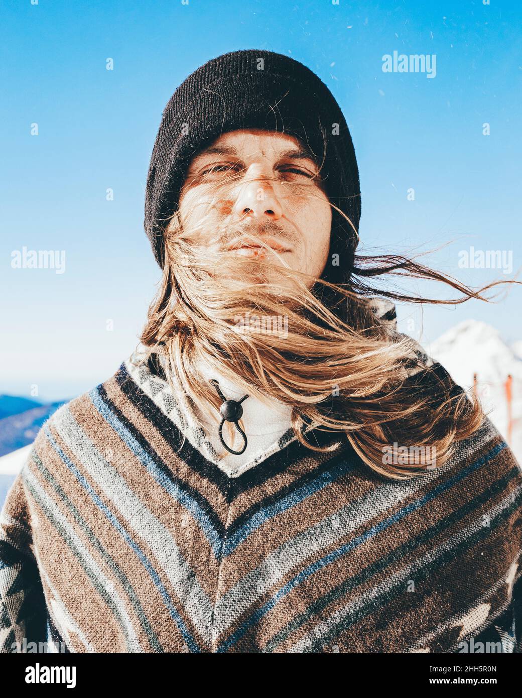 Man with poncho and knit hat on sunny day Stock Photo