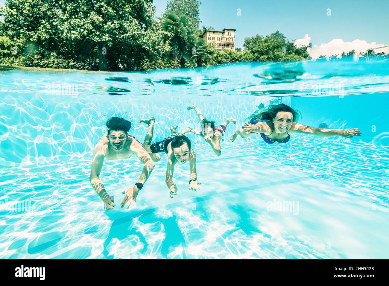 Parents swimming with children under swimming pool on sunny day Stock