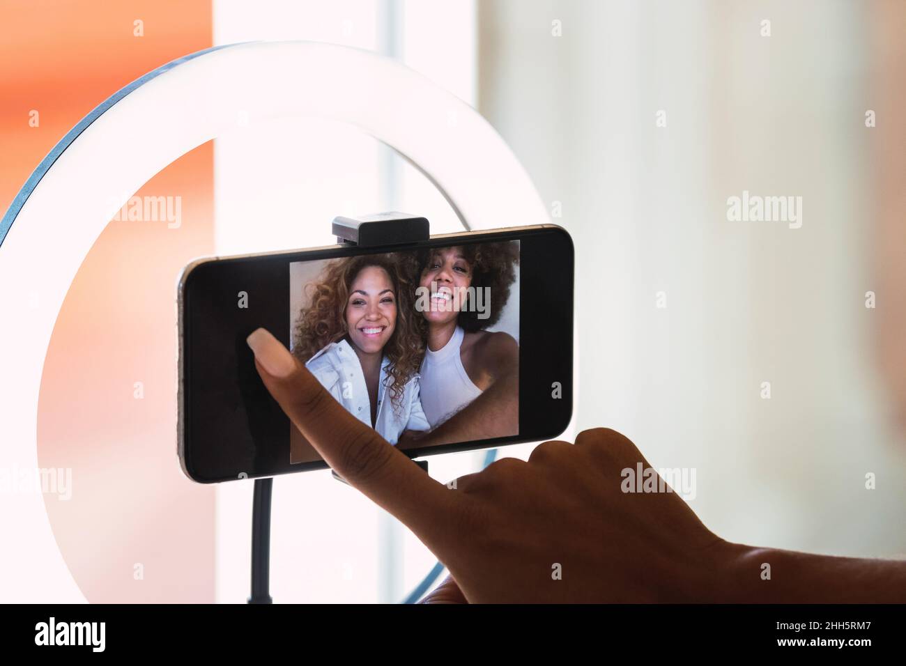 Smiling friends live streaming through smart phone at home Stock Photo