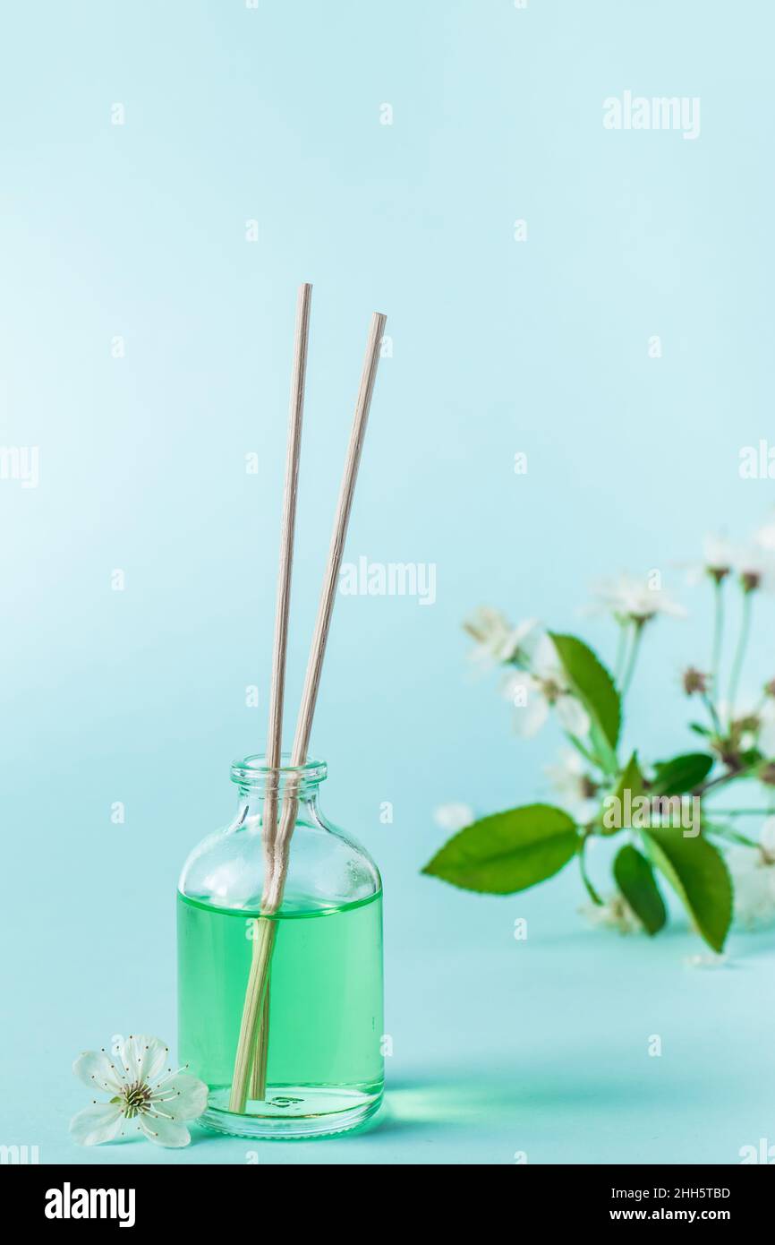 Aromatic diffuser and flowers on a blue background. Spa and relaxation concept. Fragrances for home. Place for your text. Stock Photo