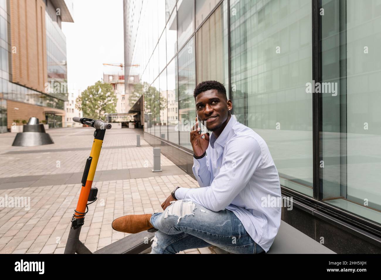 Thoughtful man talking on smart phone in front of building Stock Photo