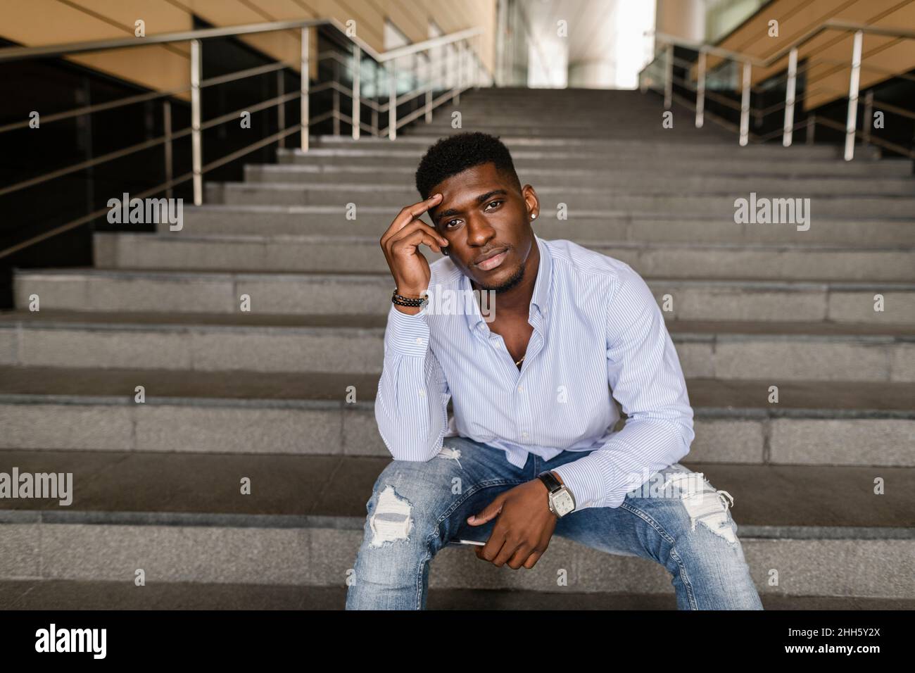 Thoughtful young man sitting on steps Stock Photo