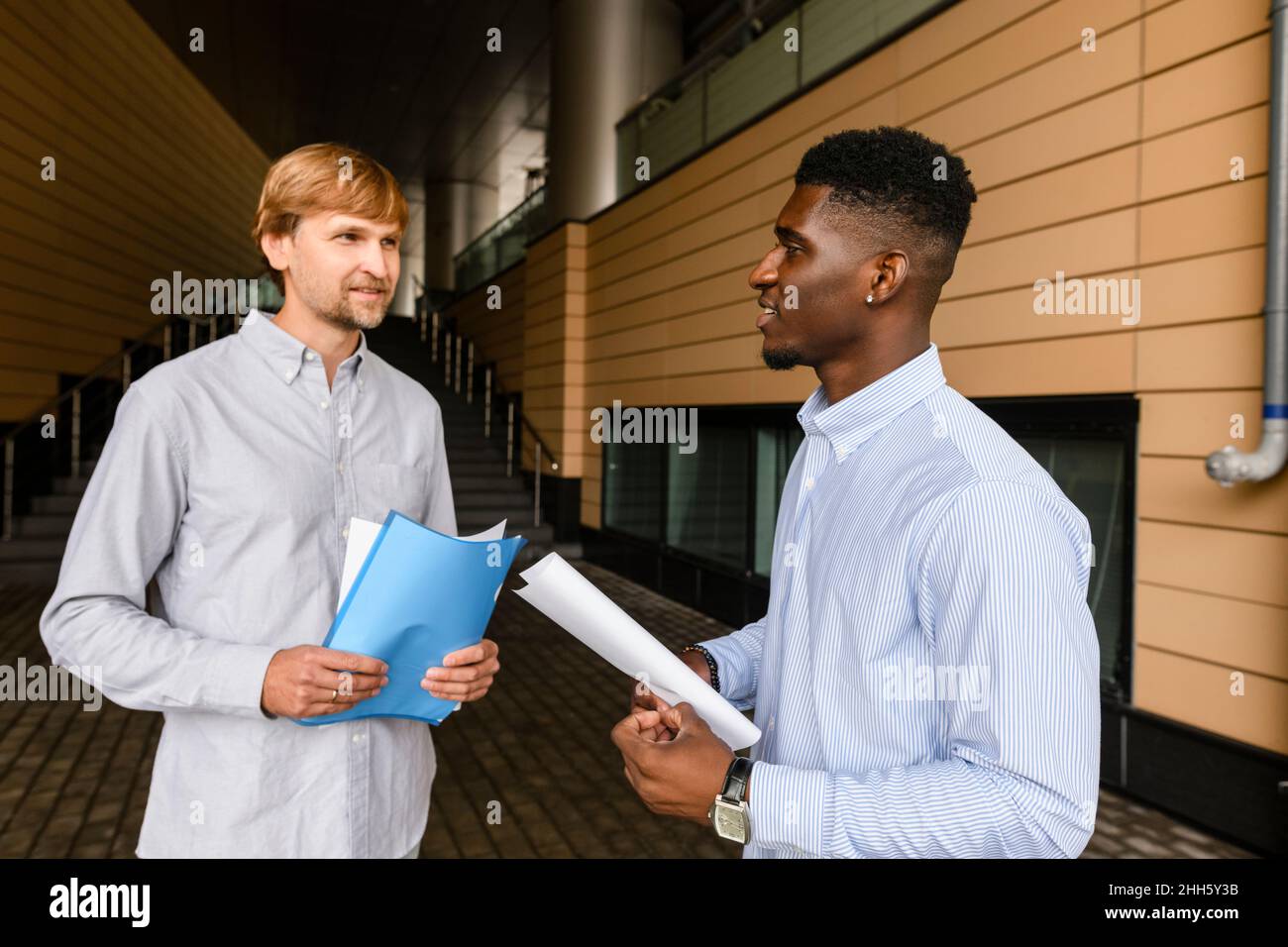 Friends with documents talking on footpath Stock Photo