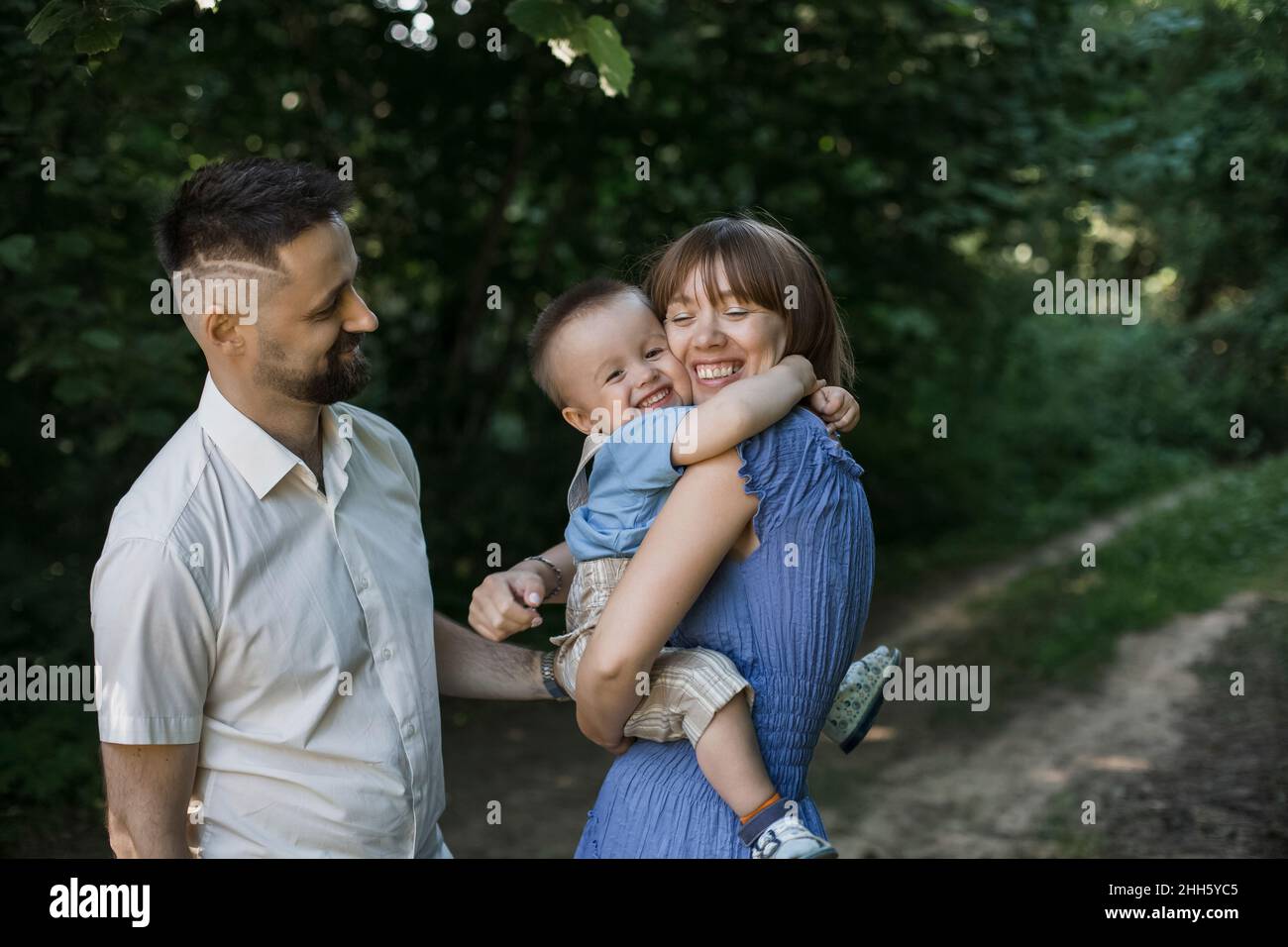 Happy mother embracing son standing by man at park Stock Photo