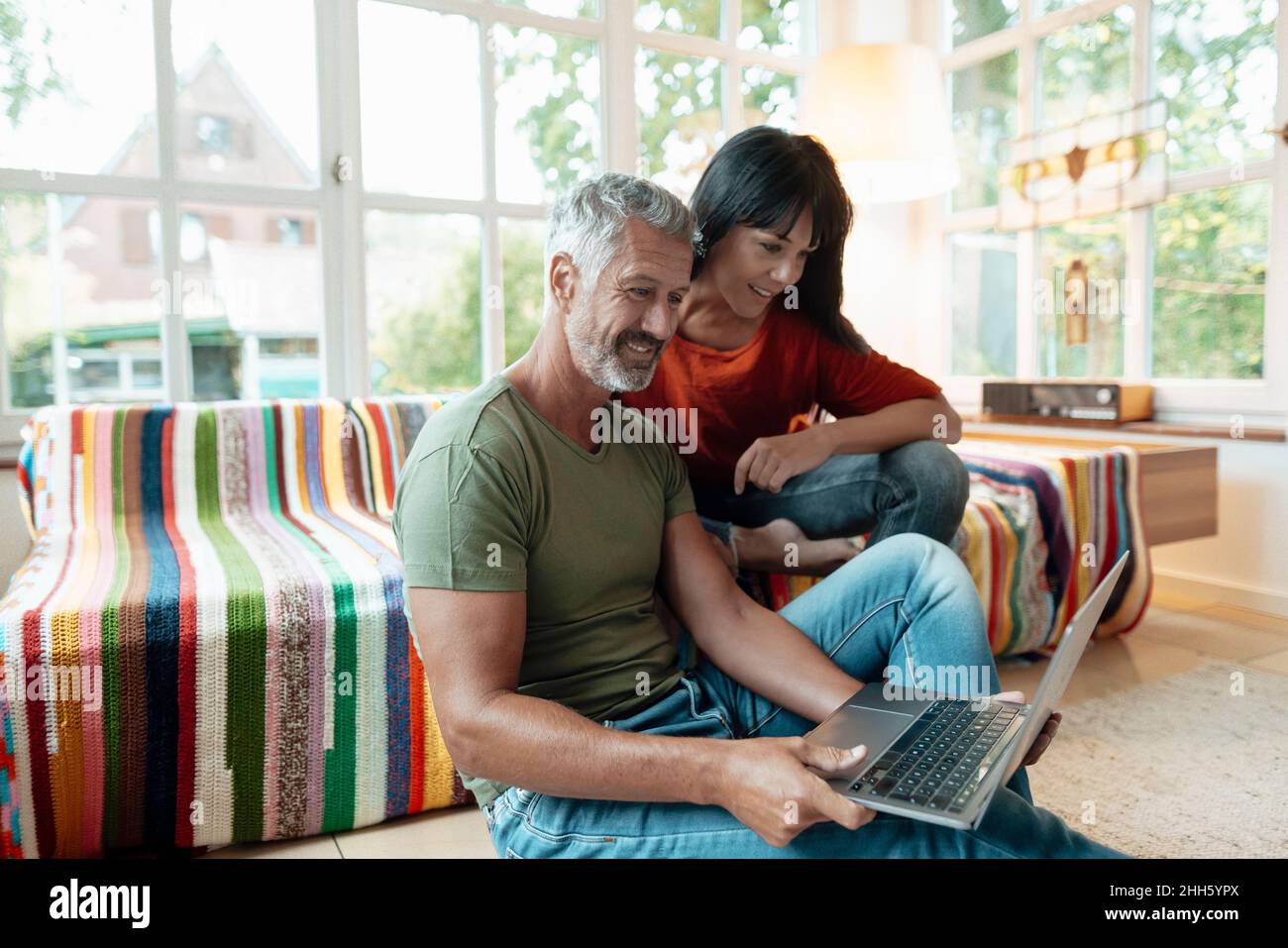 Smiling mature couple using laptop at home Stock Photo