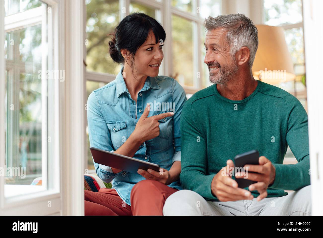 Woman holding tablet PC talking with smiling man at home Stock Photo