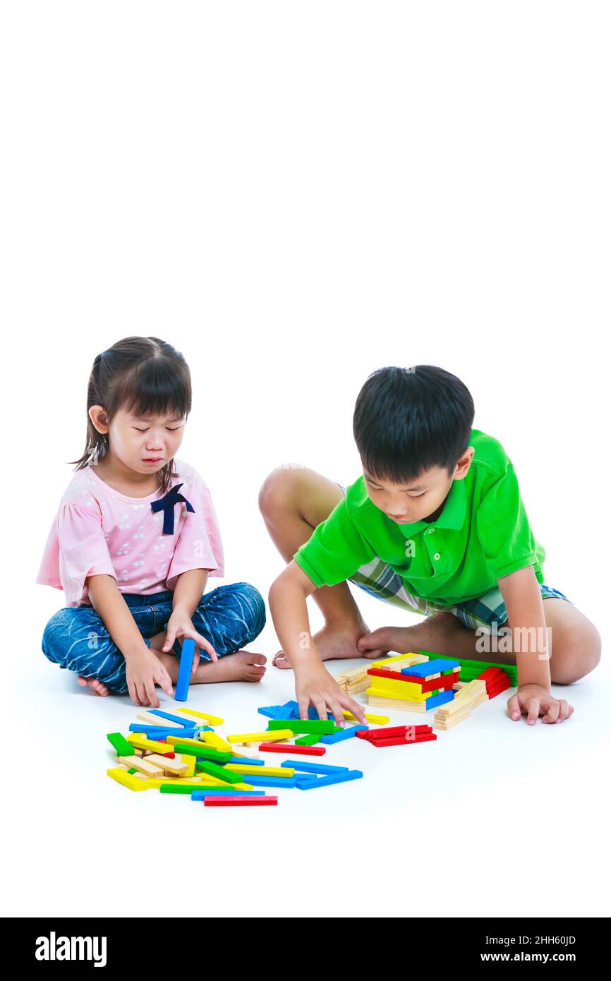 Asian children playing toy wood blocks together. Frustrated girl crying and showing moody behavior. Isolated on white background. Educational toys for Stock Photo