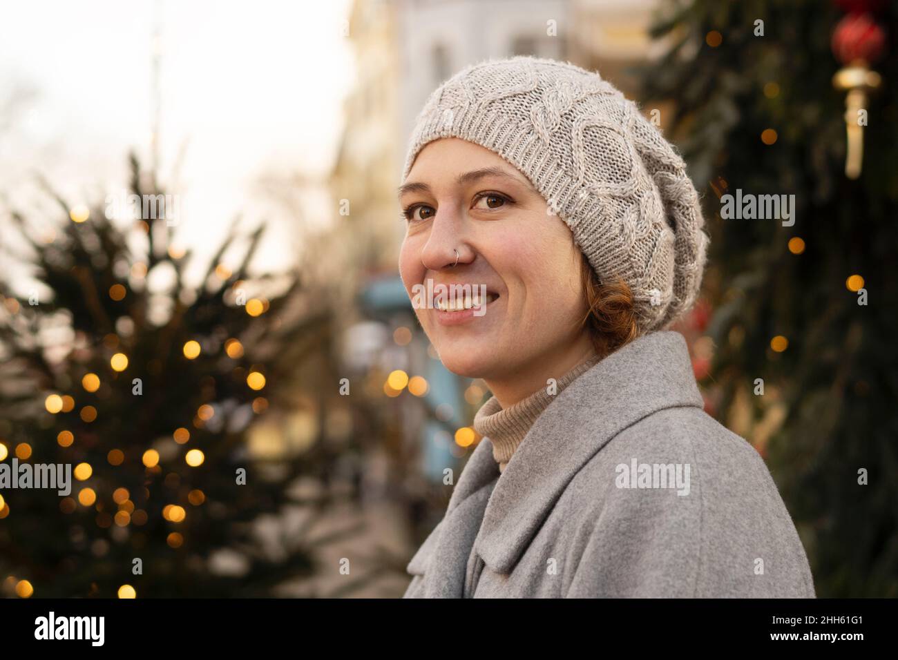 Contemplative woman with knit hat by christmas trees Stock Photo