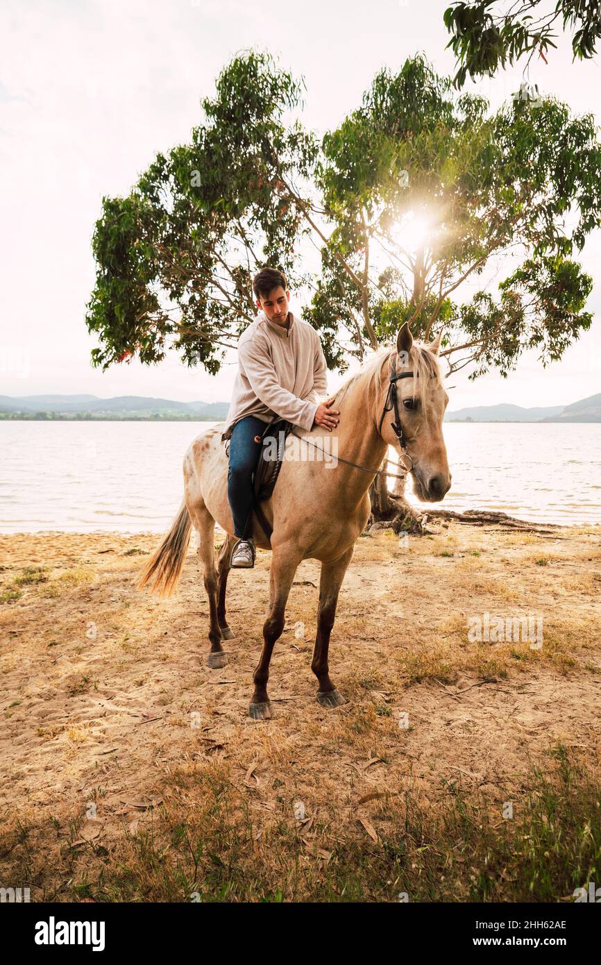Young man on horse at waterfront Stock Photo