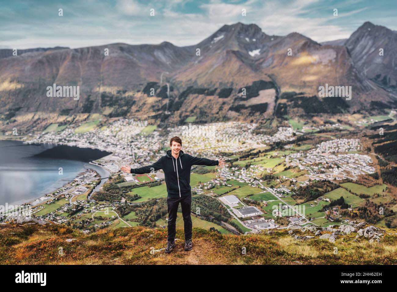 Young adult hiking man standing at the top of a mountain with arms ...
