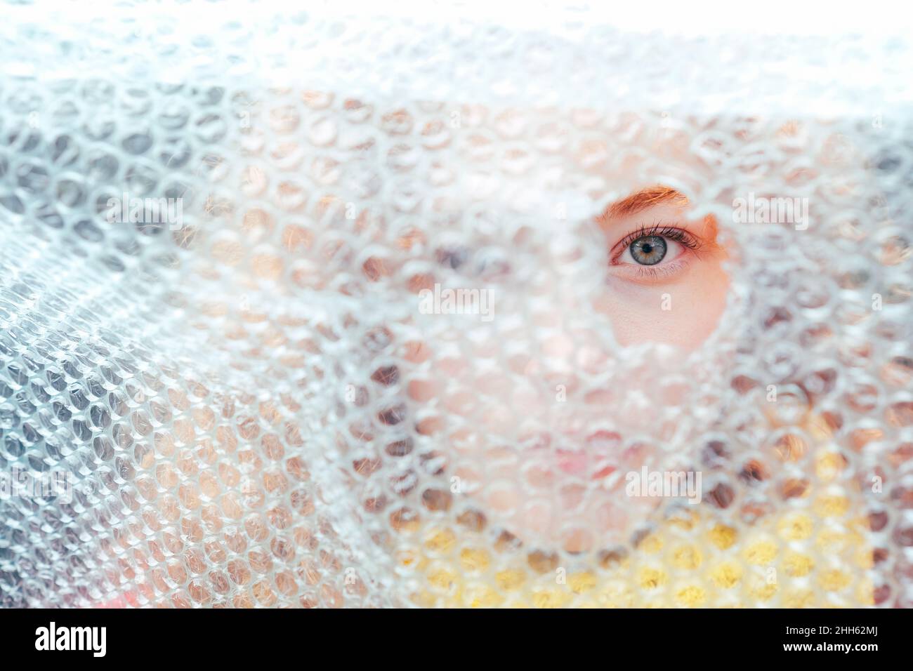 Woman looking through torn bubble wrap Stock Photo